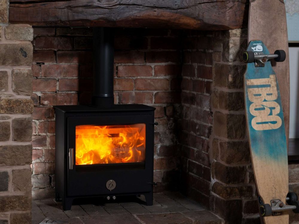 Chilli Penguin Woody wood-burning stove with heat-resistant glass ceramic door panel, fire on.